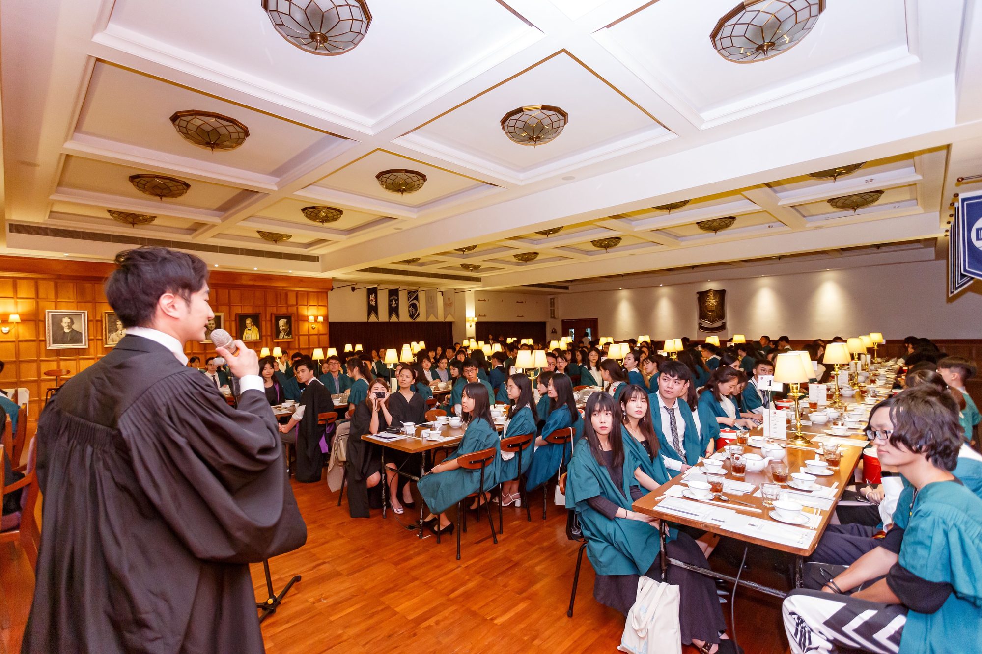 John Fung addressing a full university dining hall